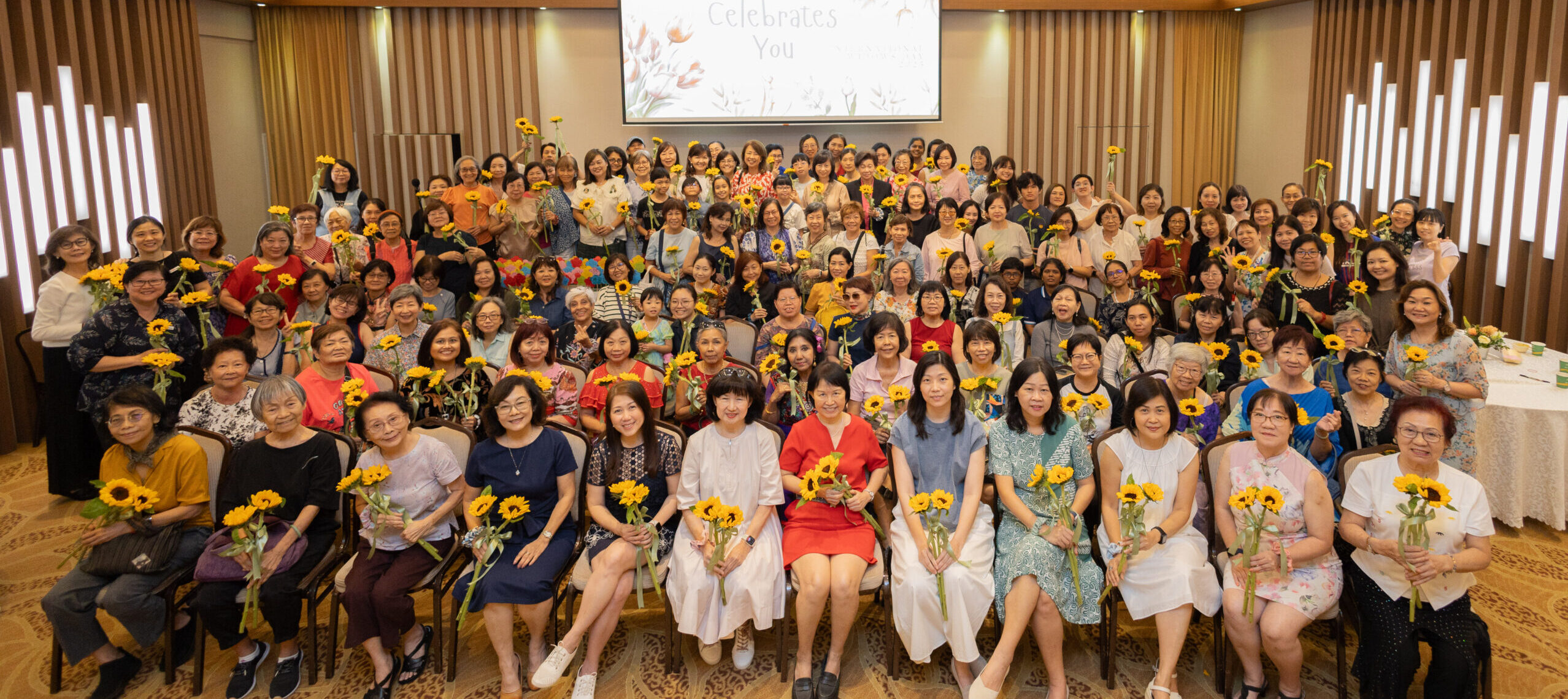 WiCare Support Group members gathered at a community event, each holding a sunflower